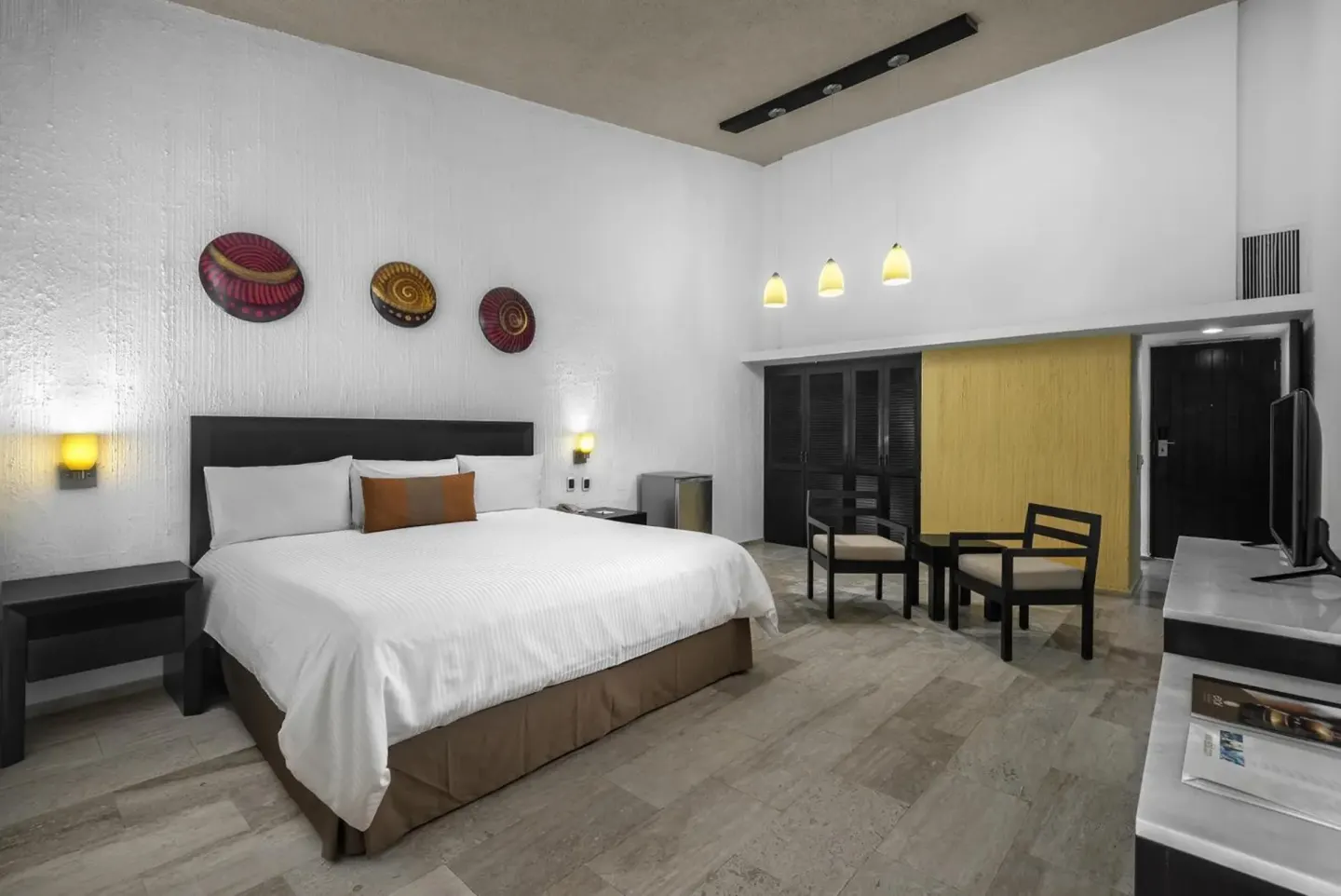 Guest room with king bed, seating area, and TV at El Cid Granada Hotel.