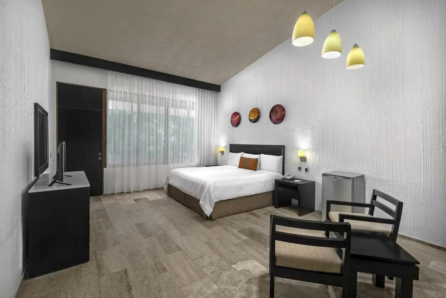 Guest room with a king bed, TV, sitting area and pendant lights at El Cid Granada Hotel.
