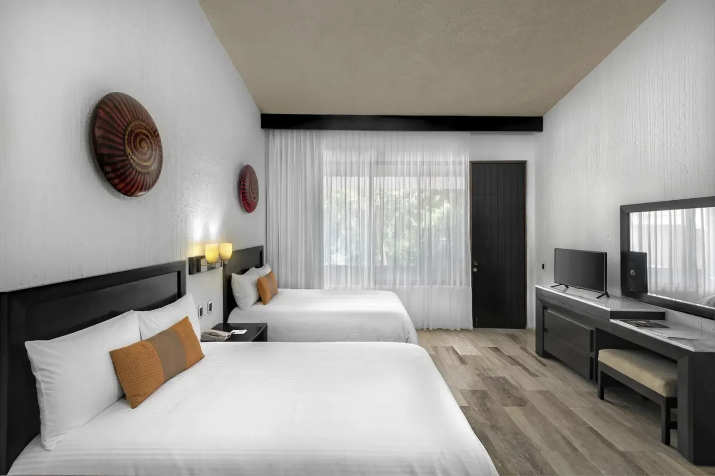 Guest room with two beds, TV, desk, and sheer-curtained window at El Cid Granada Hotel.