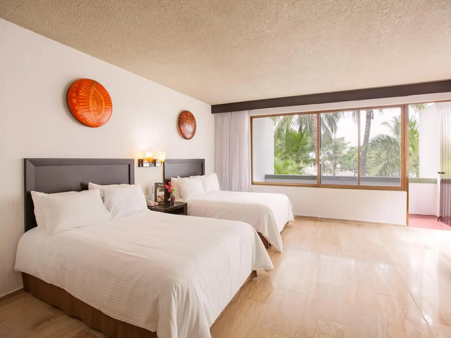Guest room with two double beds at El Cid Granada Hotel and a large window overlooking palms.