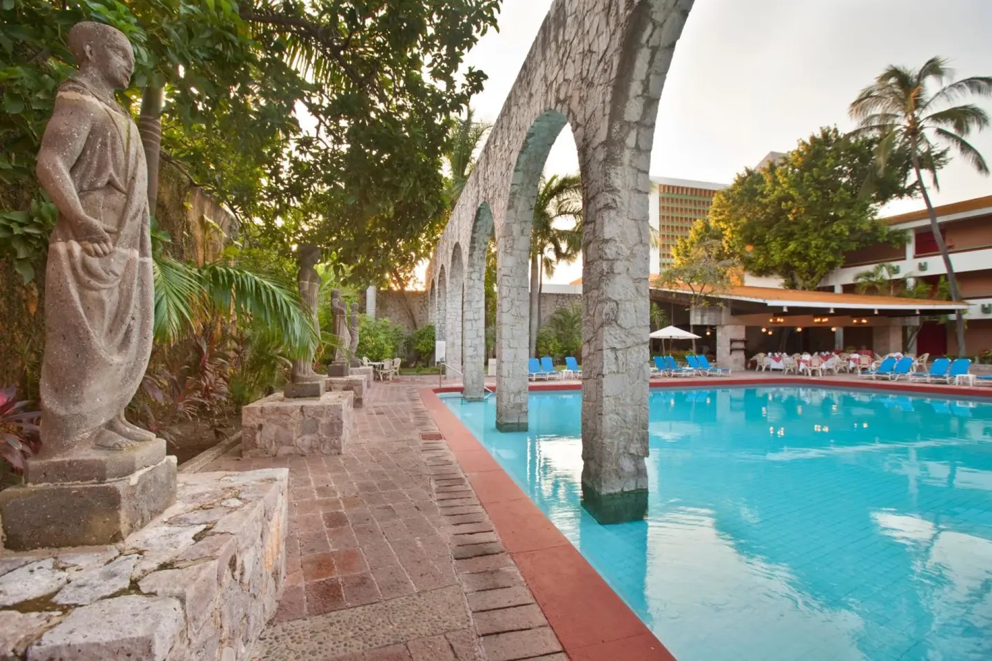 Poolside stone arches and statue beside the swimming pool at El Cid Granada Hotel.