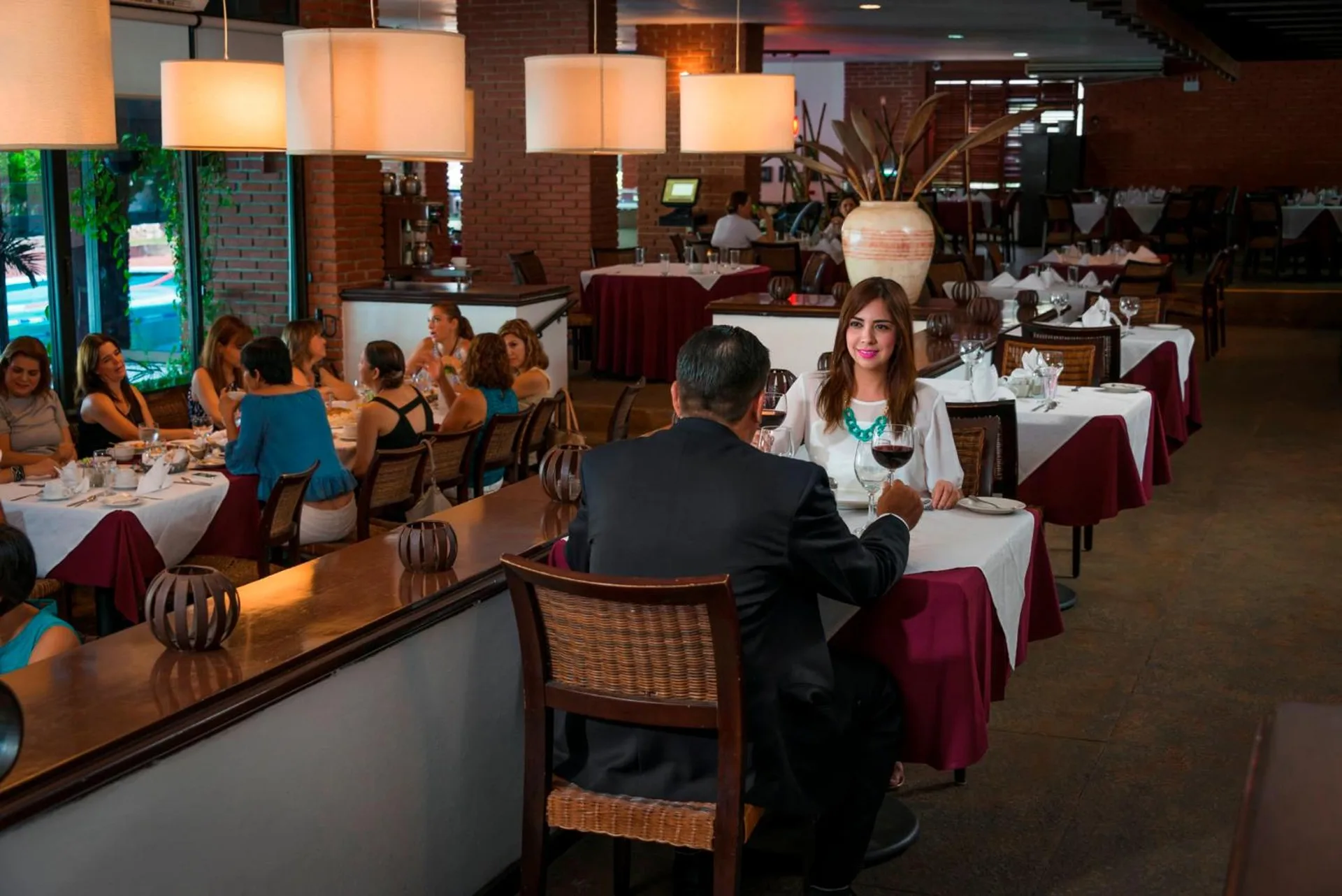 Restaurant dining room with guests, pendant lights, and set tables at El Cid Granada Hotel.