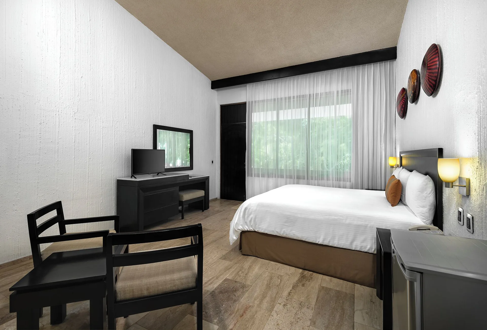 One Bedroom Suite bedroom with king bed and sitting area at El Cid Granada Hotel.
