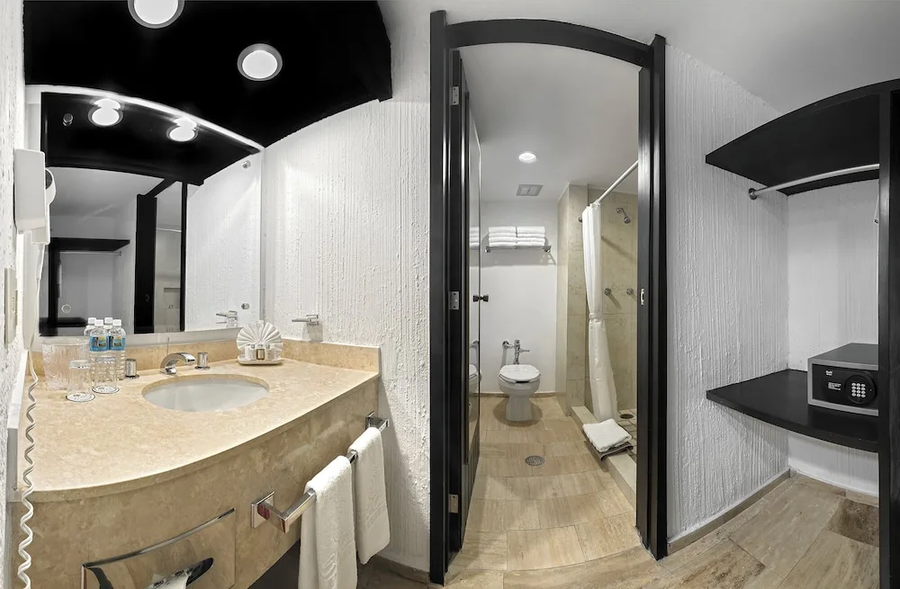 Studio bathroom vanity, shower area and closet safe at El Cid Granada Hotel.