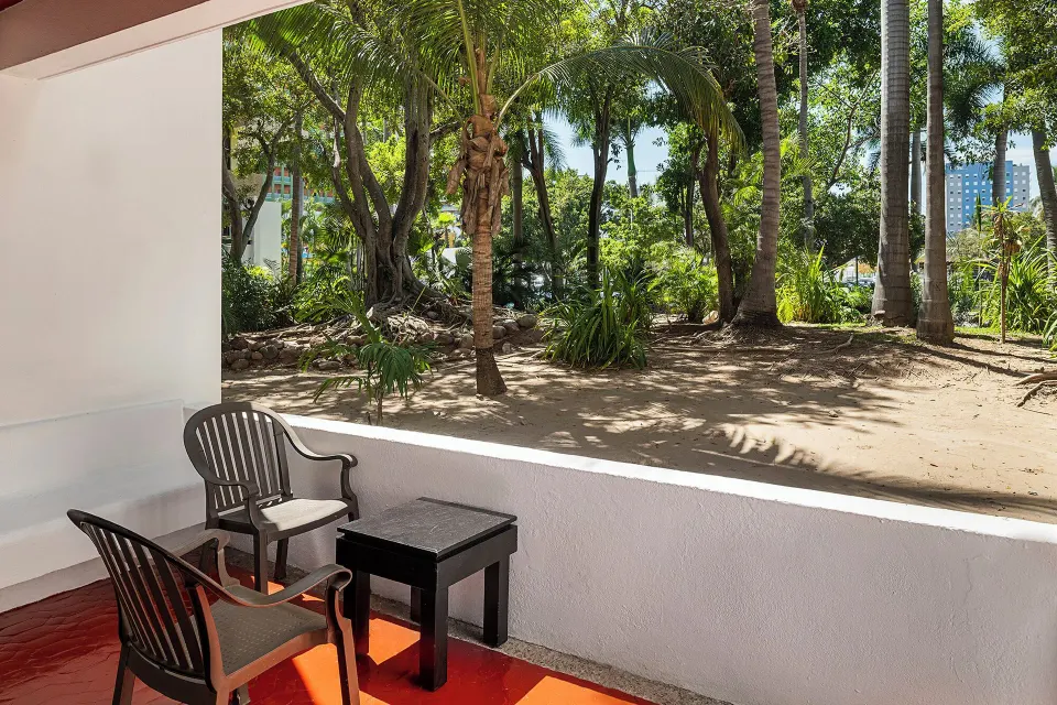 Studio patio seating beside tropical garden grounds at El Cid Granada Hotel.