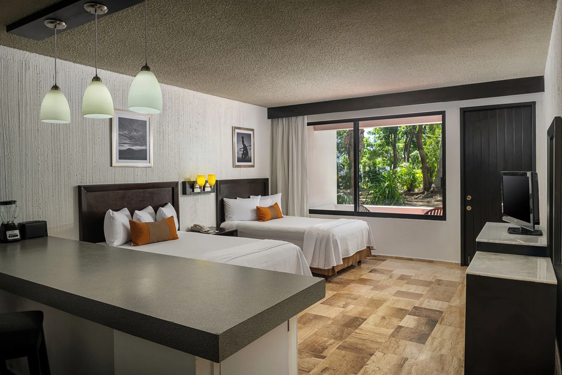 Studio with two beds, kitchenette counter and garden-facing window at El Cid Granada Hotel.