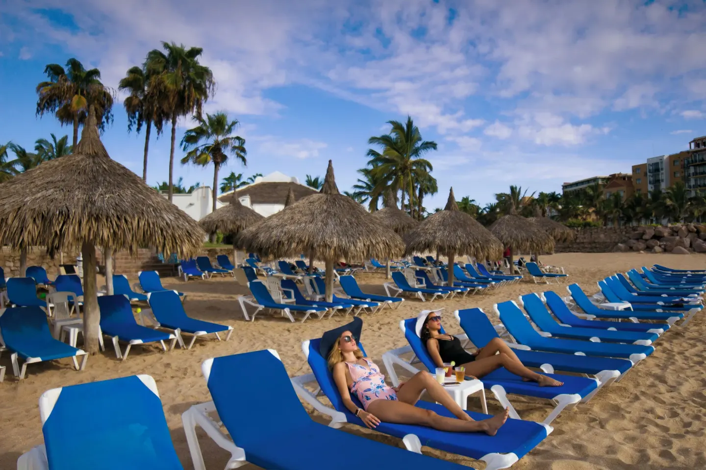 Beach loungers and thatched umbrellas on the sand at El Cid Marina Beach Hotel.