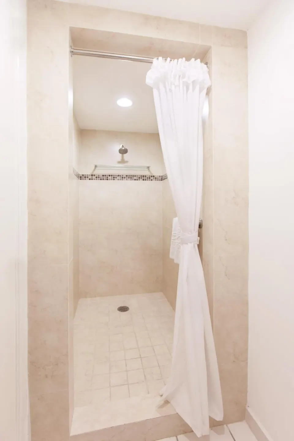 Walk-in shower with white curtain in a bathroom at El Cid Marina Beach Hotel.