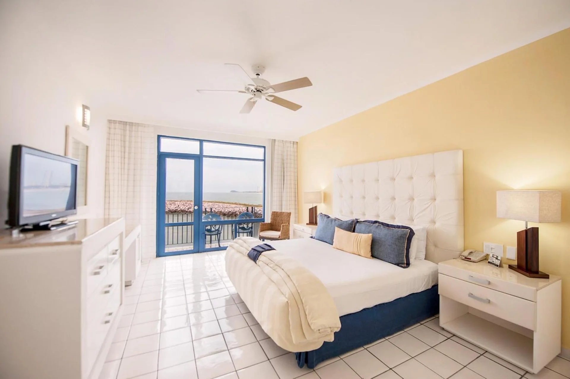 King bed guest room with balcony and ocean view at El Cid Marina Beach Hotel.