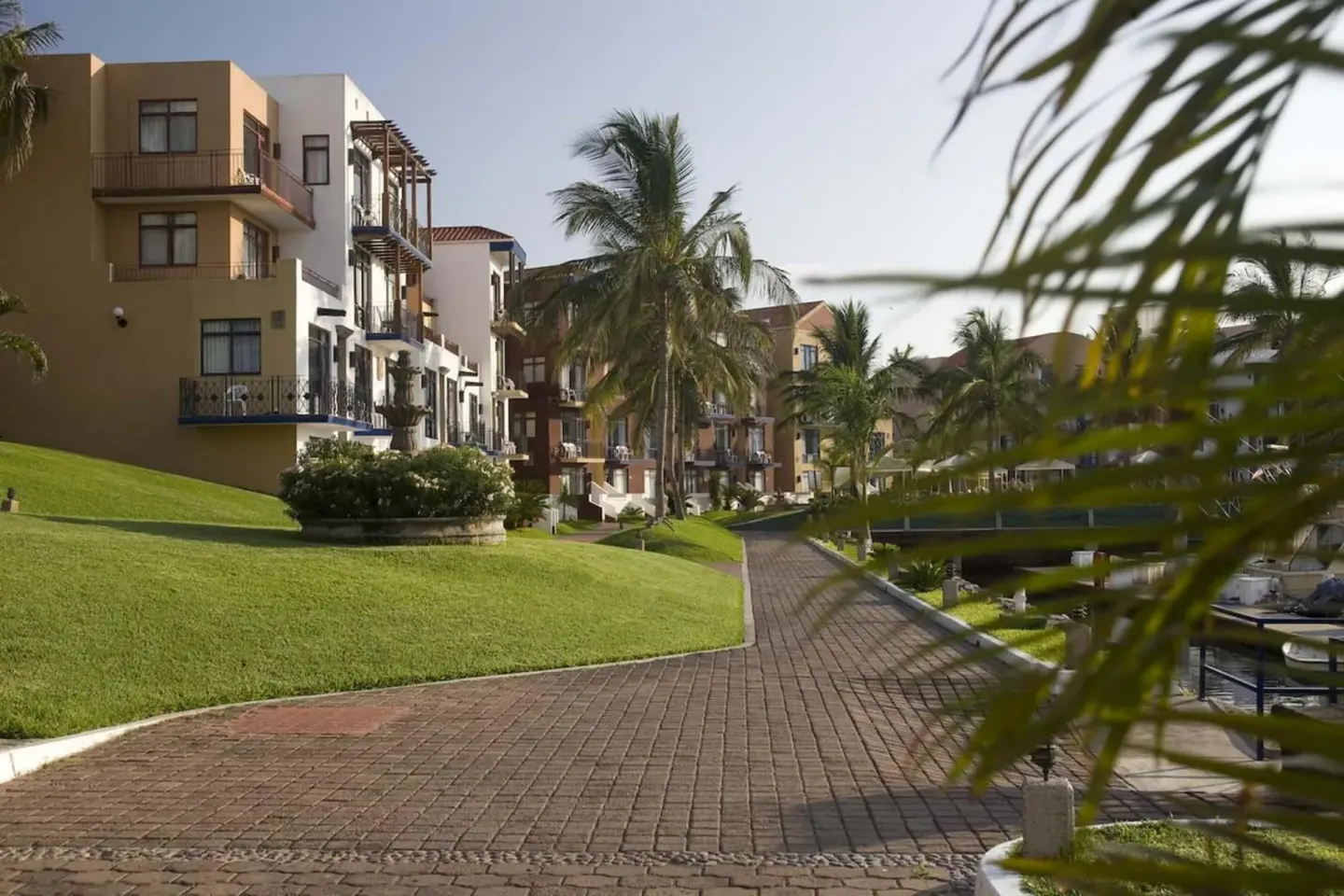 Landscaped walkway beside guestroom buildings at El Cid Marina Beach Hotel.
