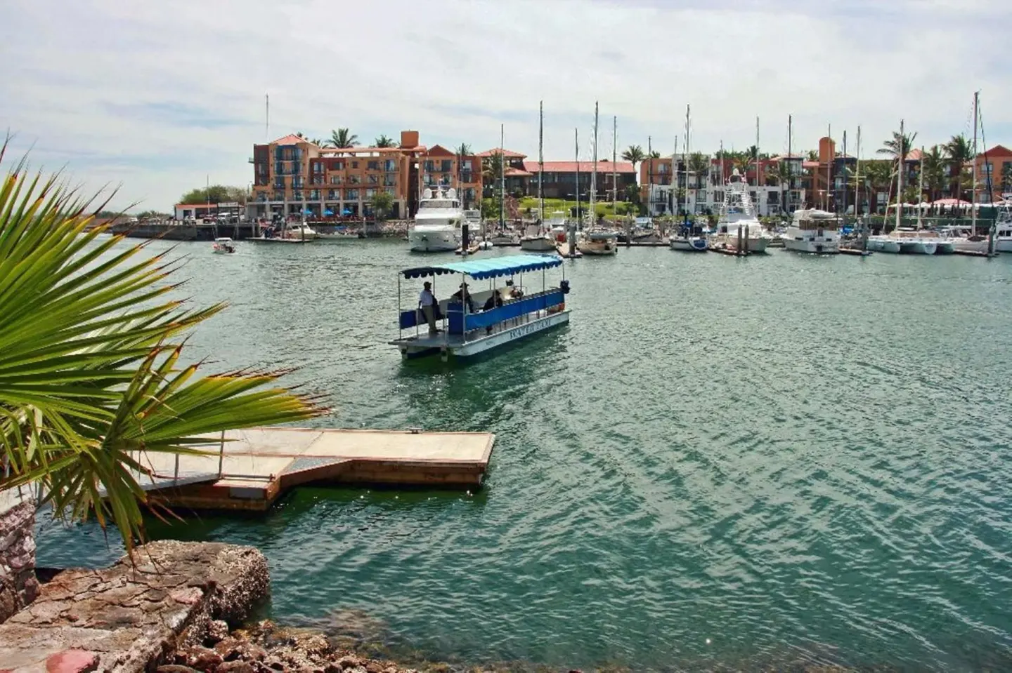 Marina with boats and a small passenger launch at El Cid Marina Beach Hotel.