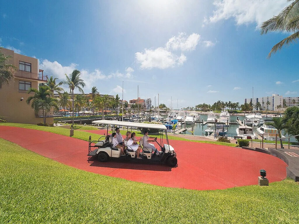 Marina path with golf cart and boats at El Cid Marina Beach Hotel.