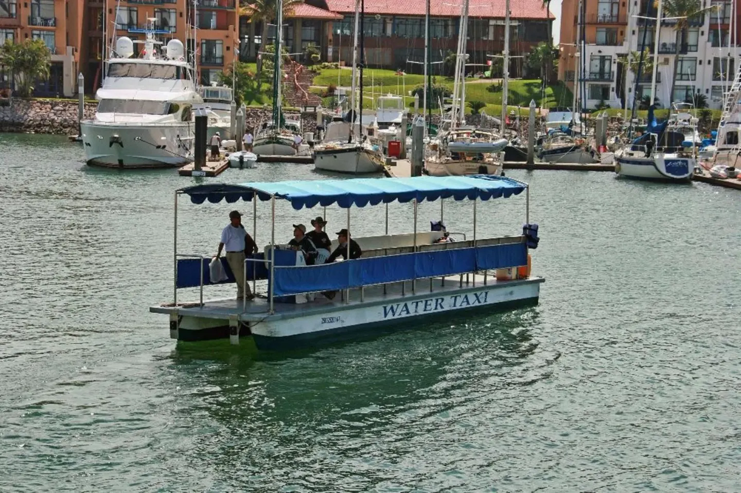 Water taxi crosses the marina in front of El Cid Marina Beach Hotel.
