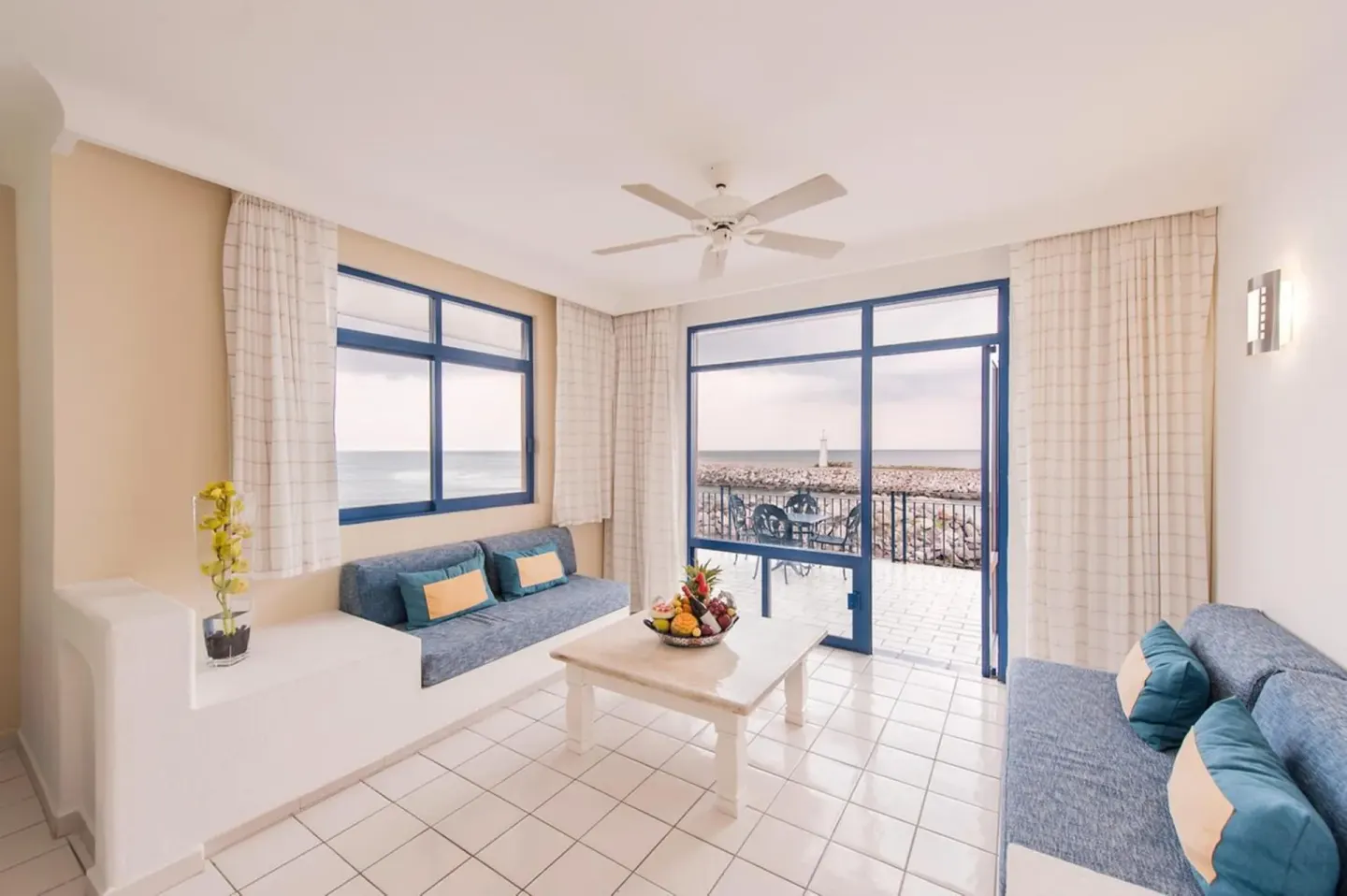 Oceanfront suite living area with blue sofas at El Cid Marina Beach Hotel.