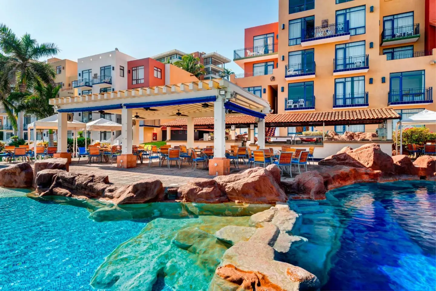 Poolside terrace and colorful guestroom buildings at El Cid Marina Beach Hotel.