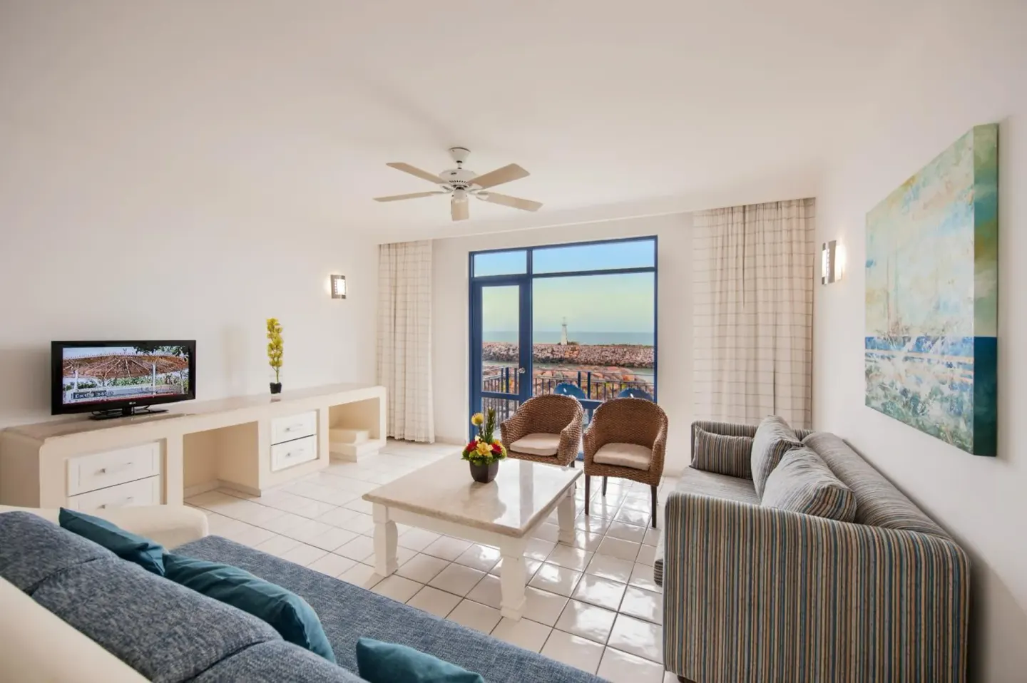 Suite living room with sofa and balcony view at El Cid Marina Beach Hotel.