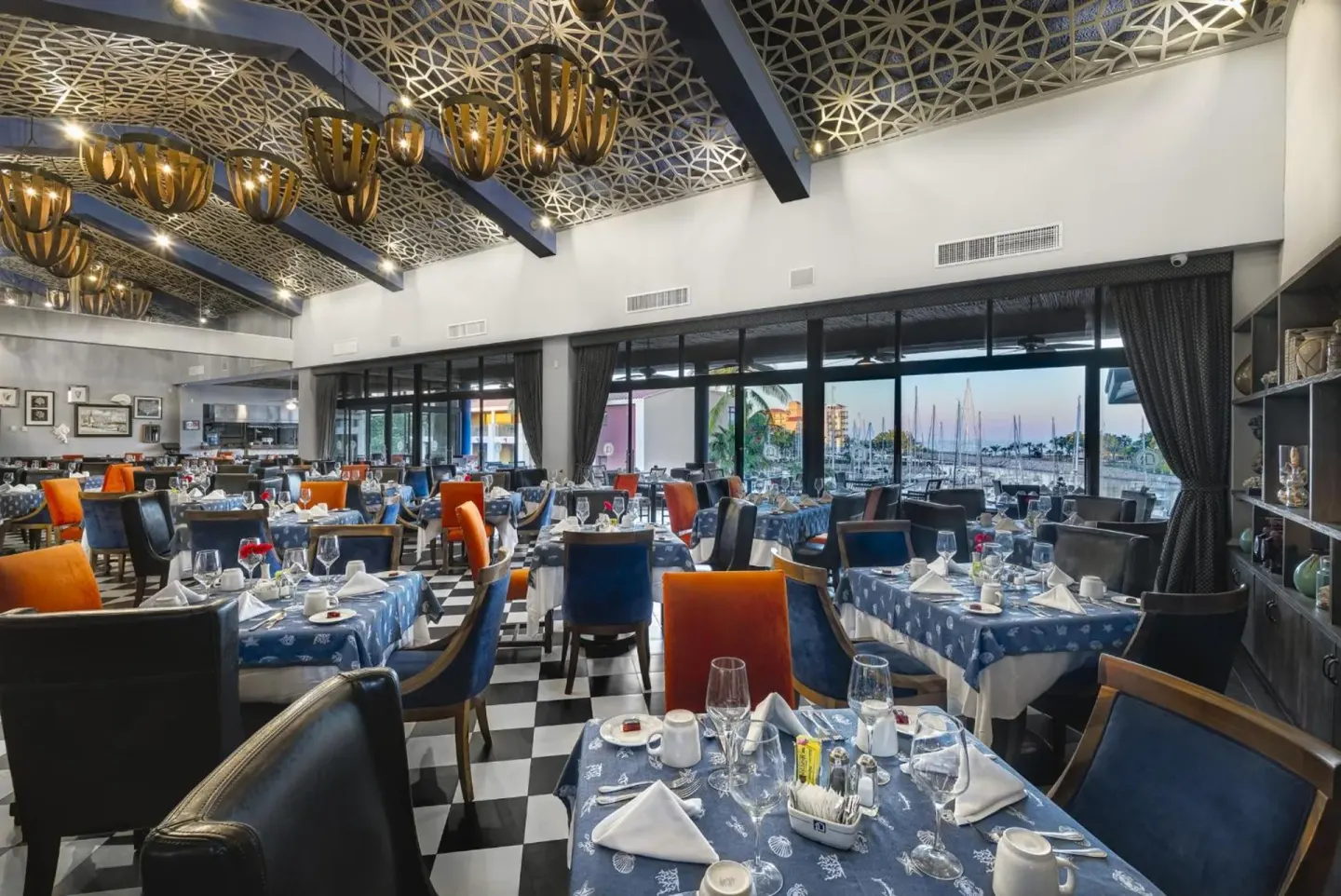 Marina-view dining room with set tables at El Cid Marina Beach Hotel.