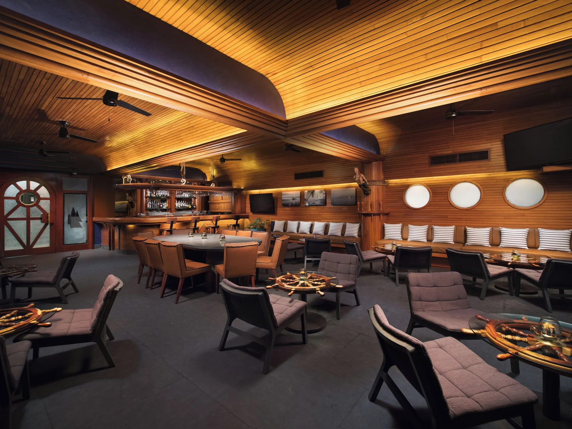 Nautical lounge bar with wood ceiling and round windows at El Cid Marina Beach Hotel.