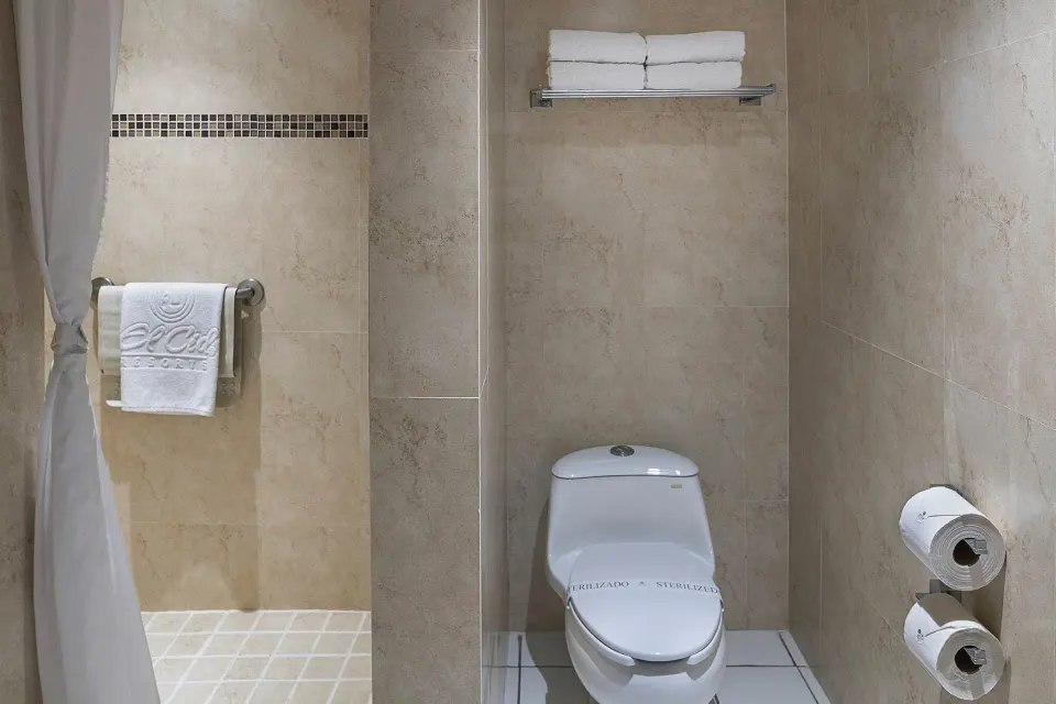 Junior Suite bathroom with toilet, towel shelf, and shower area at El Cid Marina Beach Hotel.