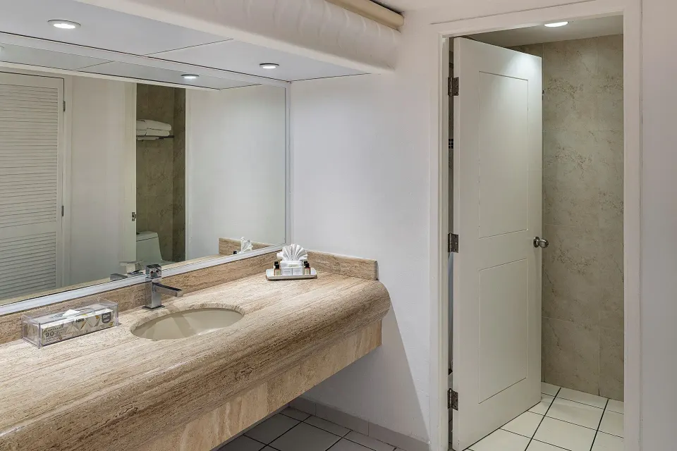 Junior Suite bathroom vanity with mirror and stone counter at El Cid Marina Beach Hotel.