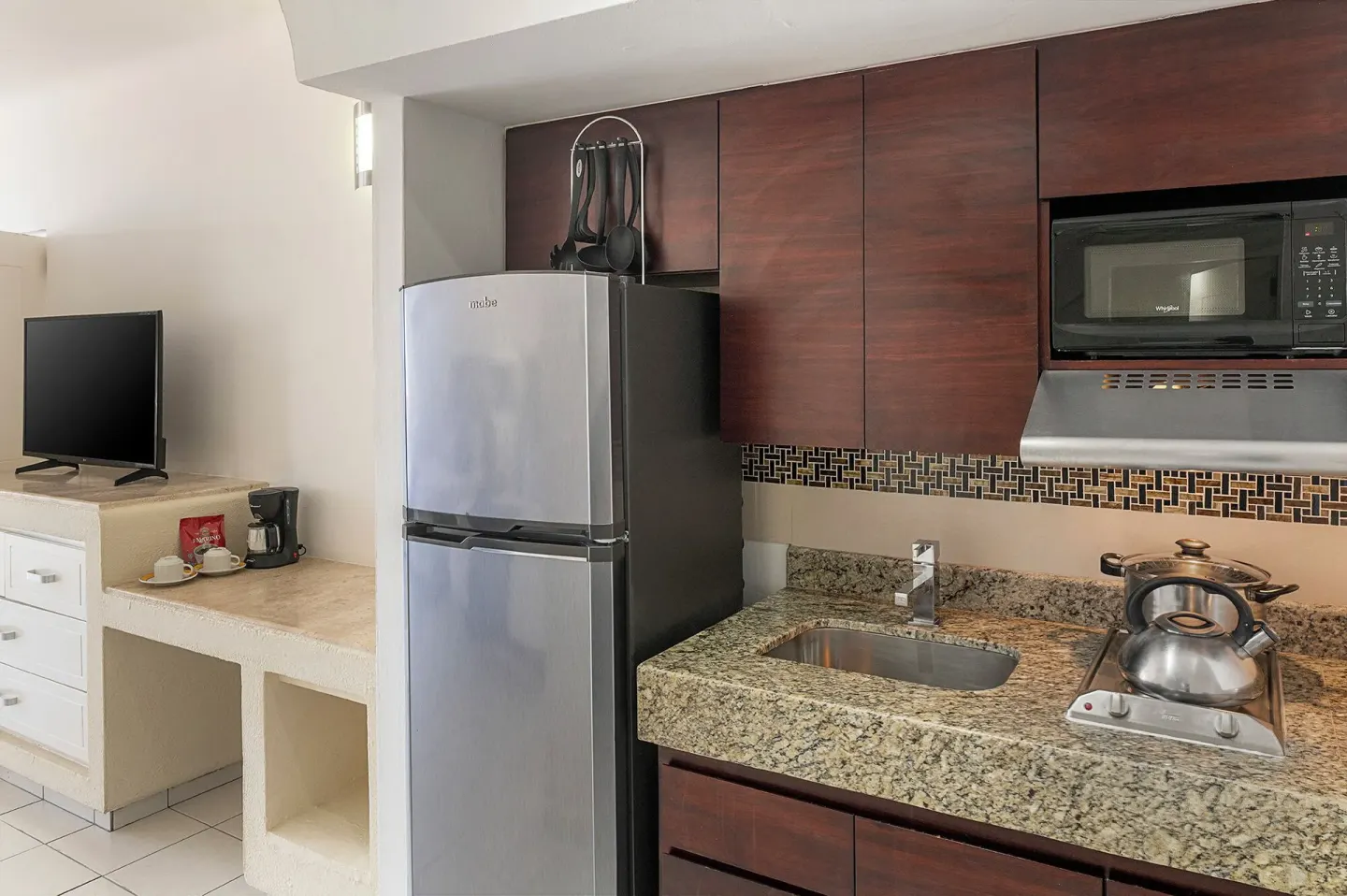 Junior Suite kitchenette with refrigerator, sink, microwave, and cooktop at El Cid Marina Beach Hotel.