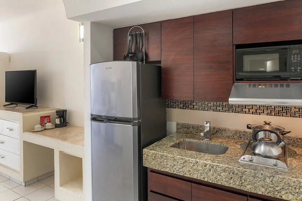 Junior Suite kitchenette with refrigerator, sink, microwave, and cooktop at El Cid Marina Beach Hotel.