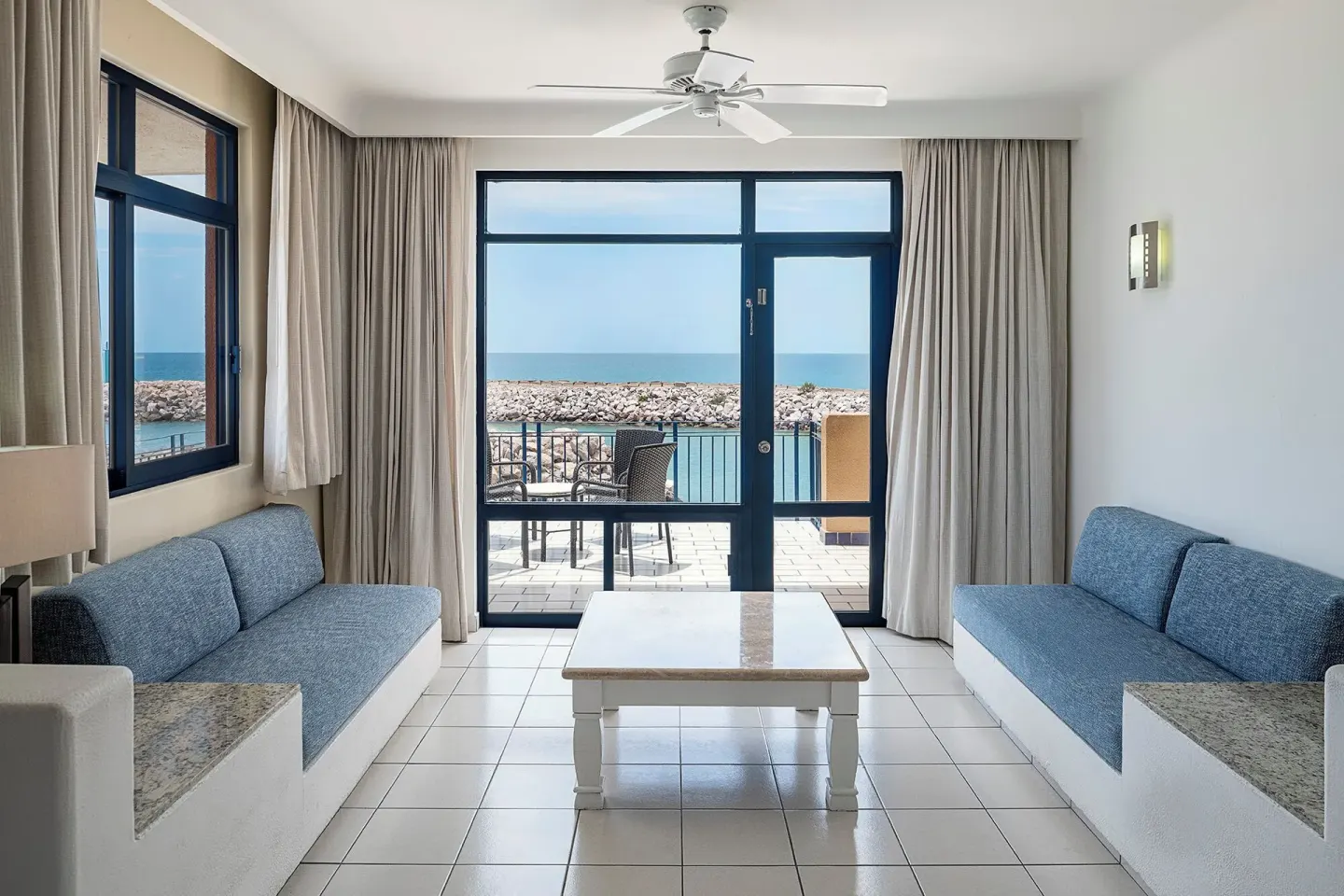 Junior Suite sitting area with sofas and balcony facing the water at El Cid Marina Beach Hotel.