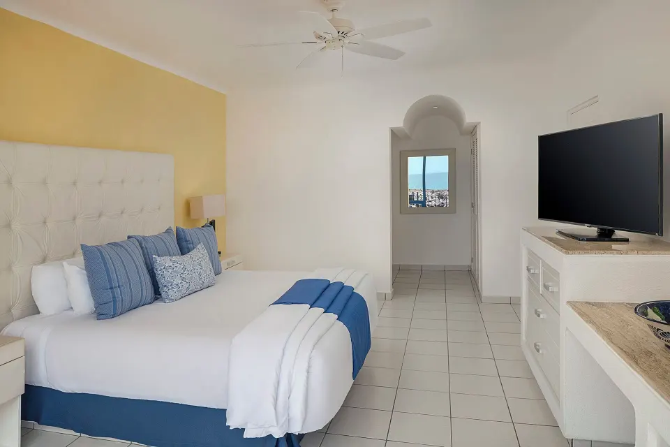 One Bedroom Suite king bed with dresser and TV at El Cid Marina Beach Hotel.