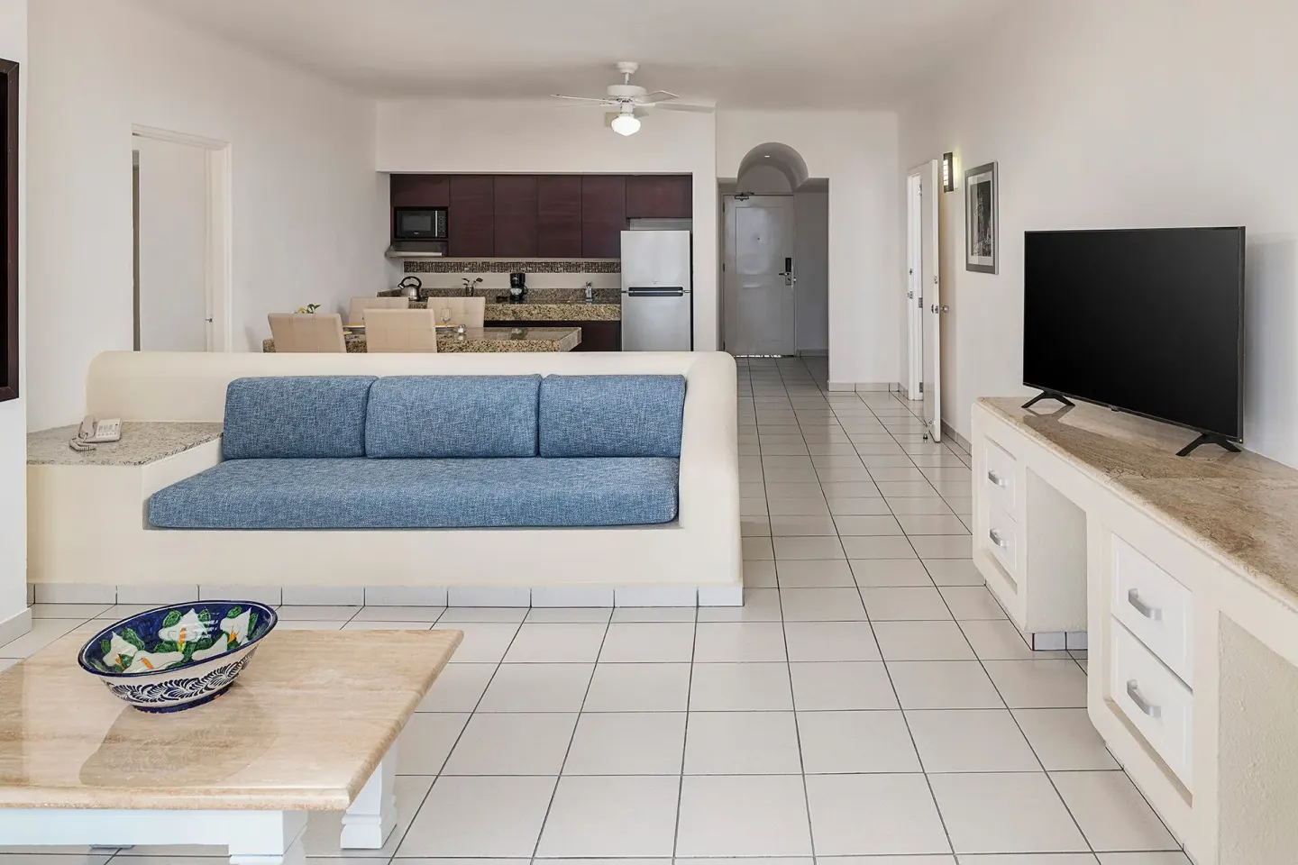 One Bedroom Suite living area with sofa and kitchen at El Cid Marina Beach Hotel.