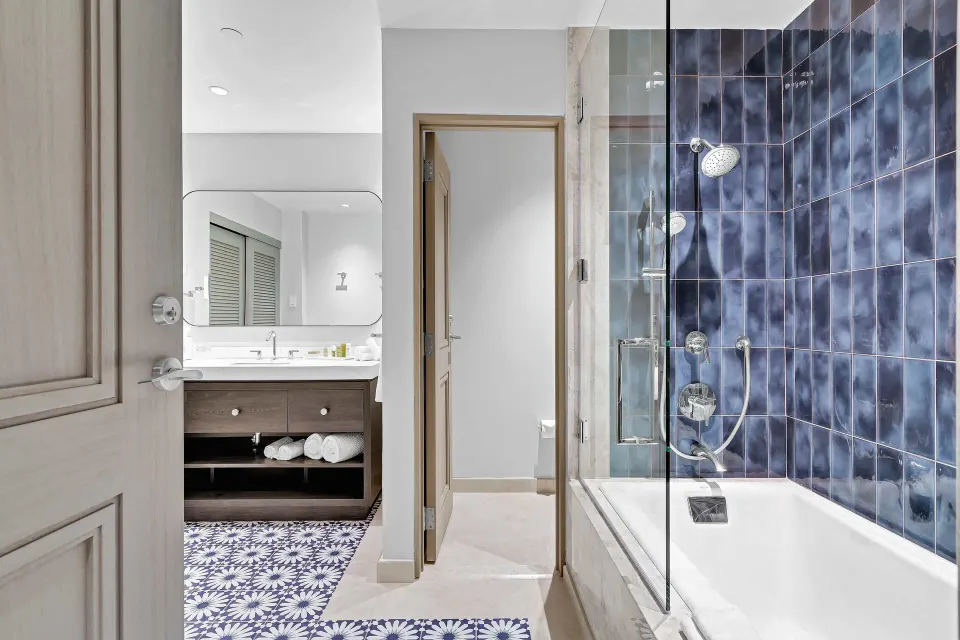 Bathroom with blue tiled tub, glass shower panel, and vanity at El Conquistador Resort.