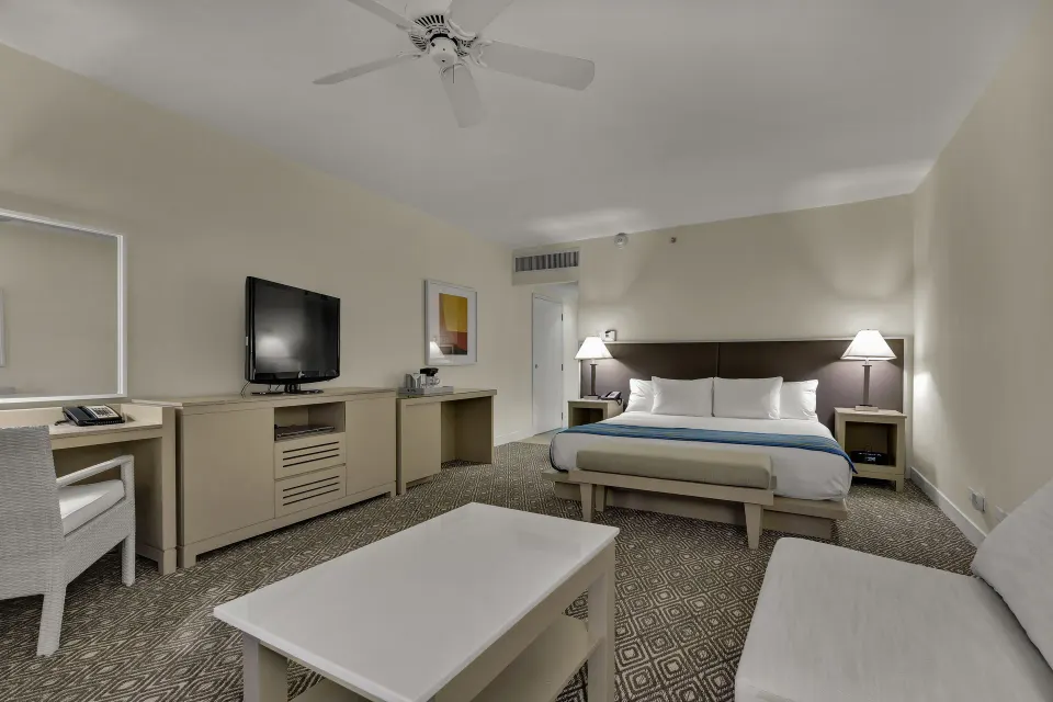 King bed guest room with sofa seating and TV at El Conquistador Resort.
