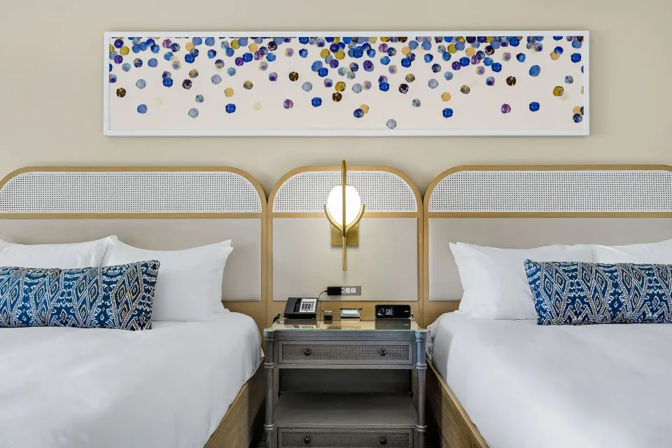 Two-bed guest room with modern seating and TV at El Conquistador Resort.