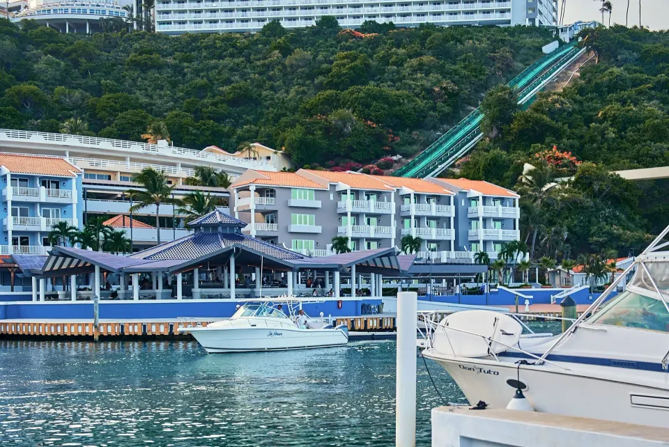 Marina with boats, waterfront buildings, and hillside funicular at El Conquistador Resort.