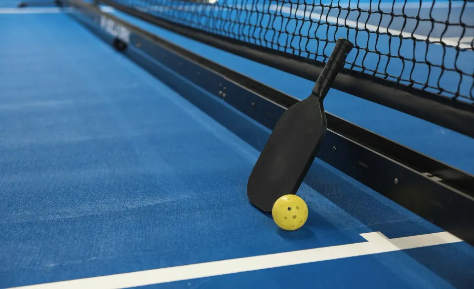 Pickleball paddle and ball by the net on a blue court at El Conquistador Resort.