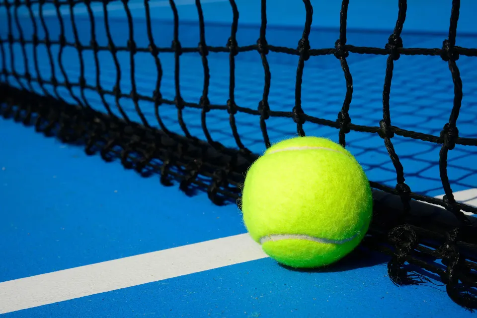 Tennis ball resting beside the net on a blue court at El Conquistador Resort.