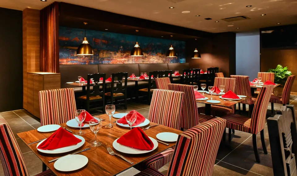 Restaurant tables with red napkins and striped chairs at El Conquistador Resort.
