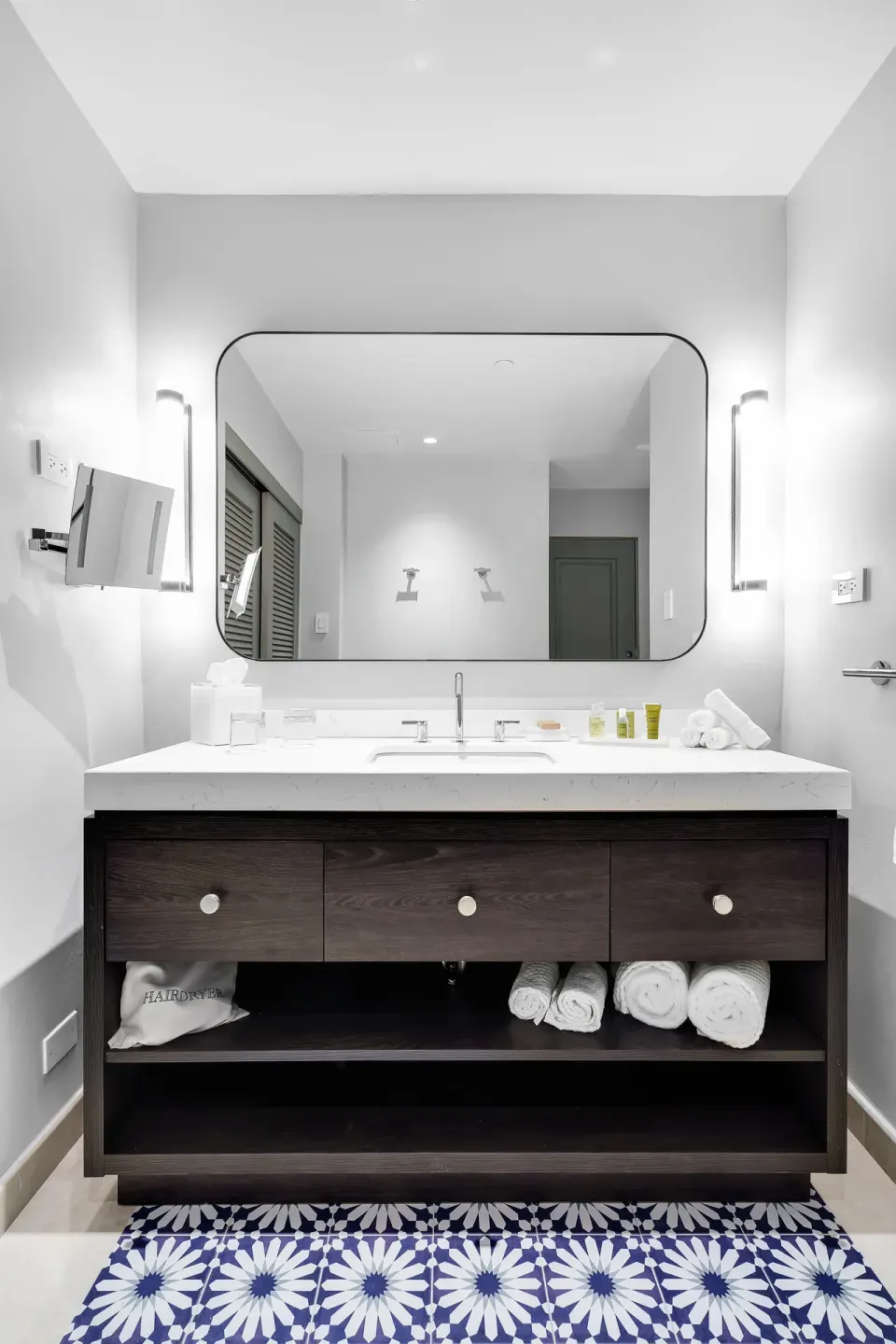 Suite bathroom vanity with large mirror and patterned rug at El Conquistador Resort.
