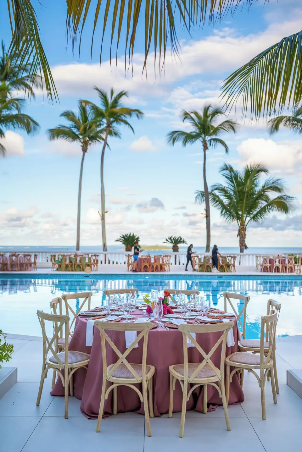 Outdoor event table by the pool and palm-lined ocean at El Conquistador Resort.