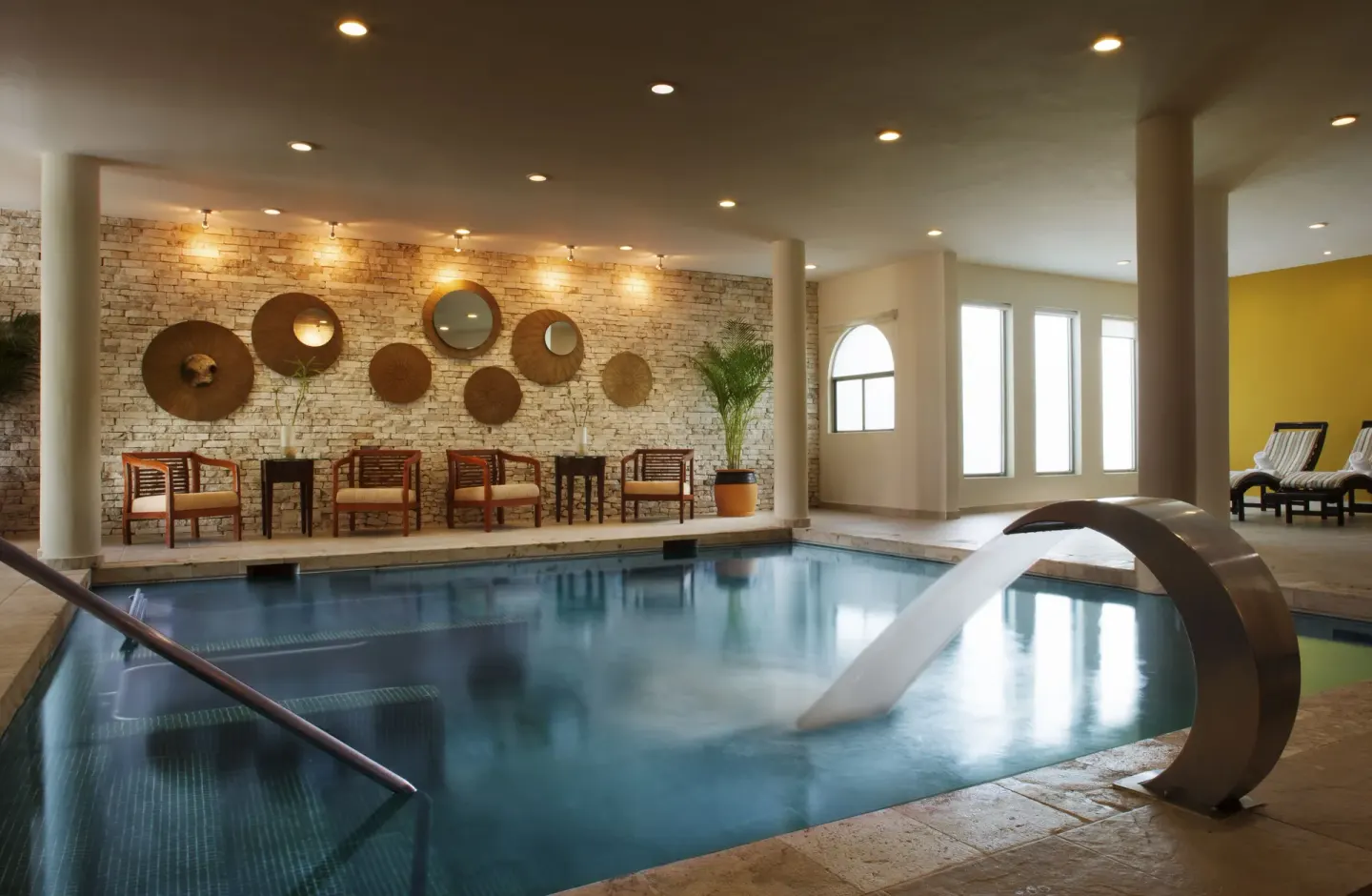 Indoor hydrotherapy pool with arched fountain and lounge chairs at El Dorado Casitas Royale.