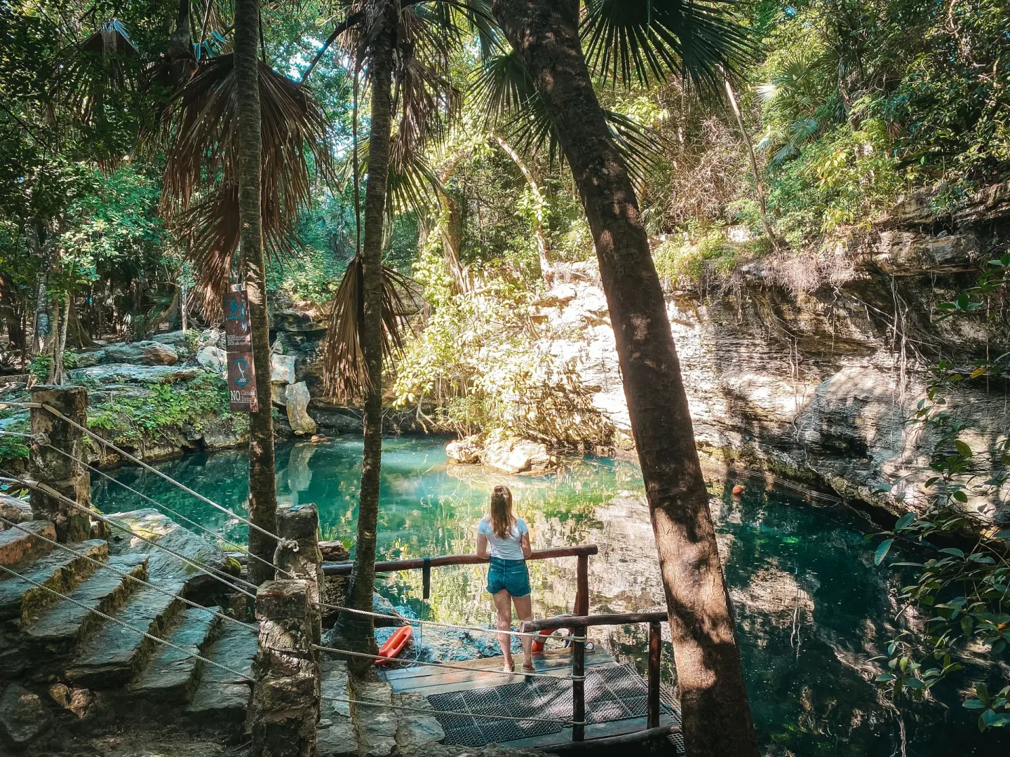Natural cenote pool surrounded by trees and rock ledges at El Dorado Casitas Royale.