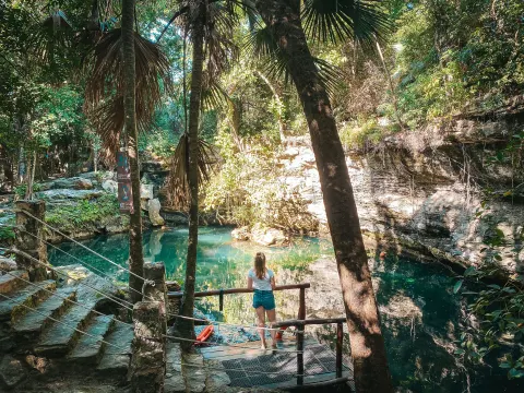 Natural cenote pool surrounded by trees and rock ledges at El Dorado Casitas Royale.