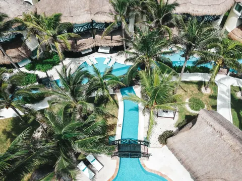 Aerial view of palm-lined pools and thatched casitas at El Dorado Casitas Royale.