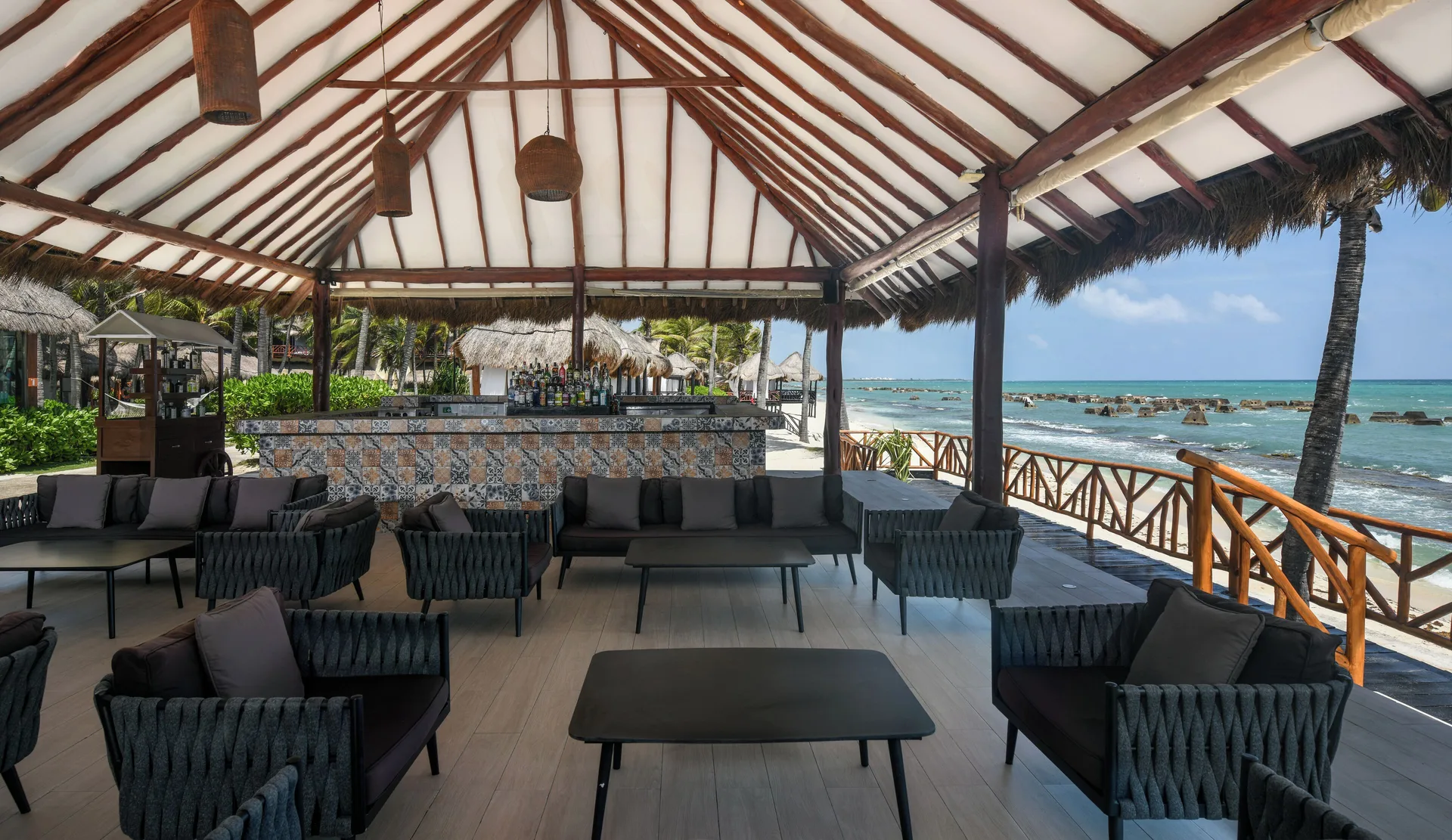 Beachfront open-air bar with lounge seating and ocean views at El Dorado Casitas Royale.