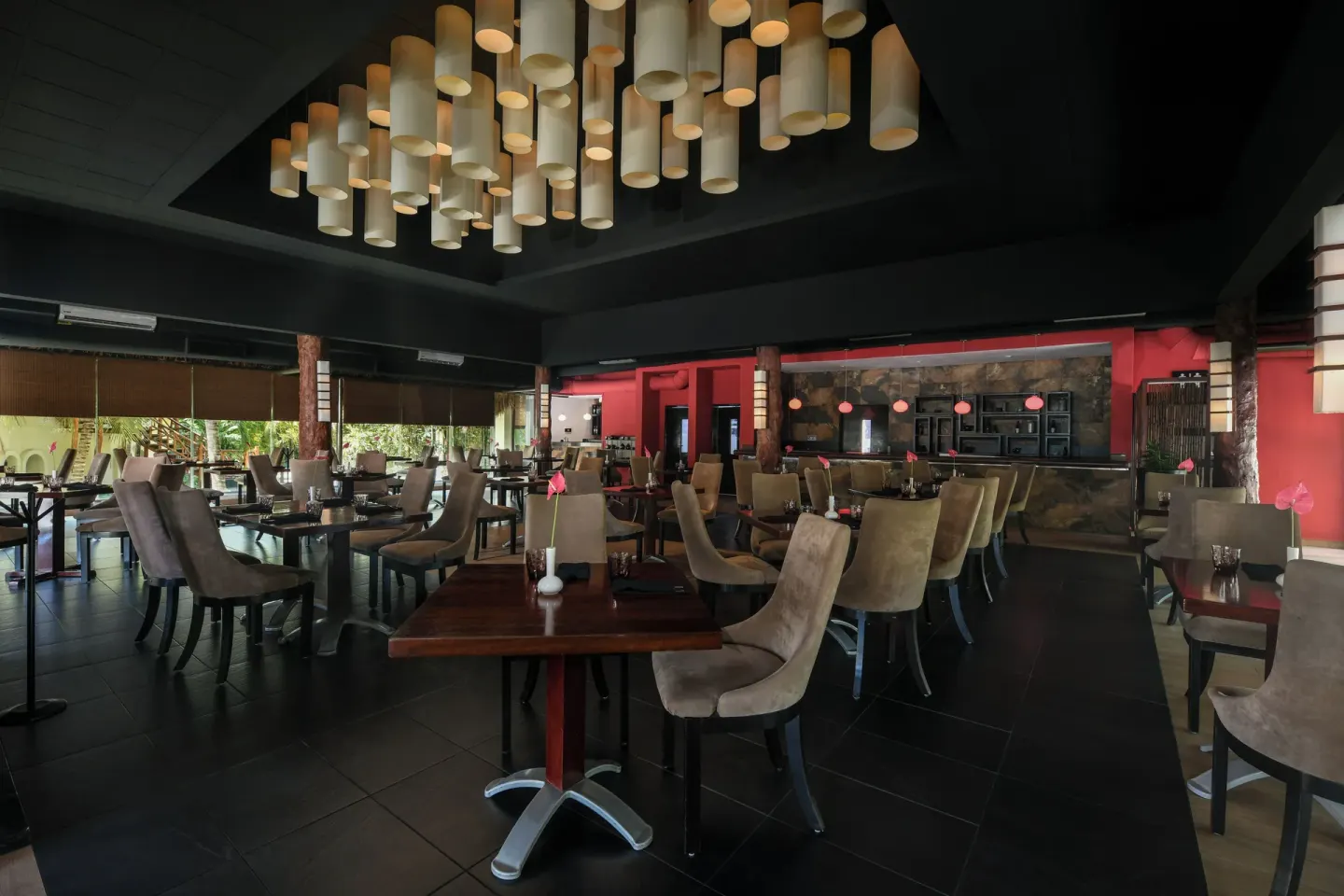 A dark-toned restaurant with pendant lights and red accents at El Dorado Casitas Royale.