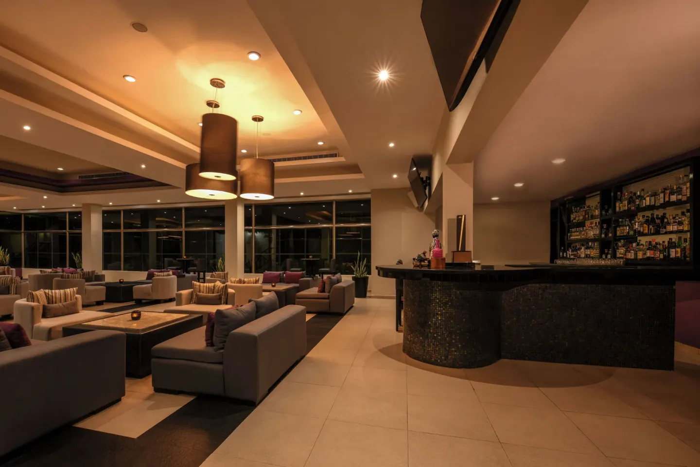 Lounge bar with sofas, pendant lights, and a curved counter at El Dorado Casitas Royale.