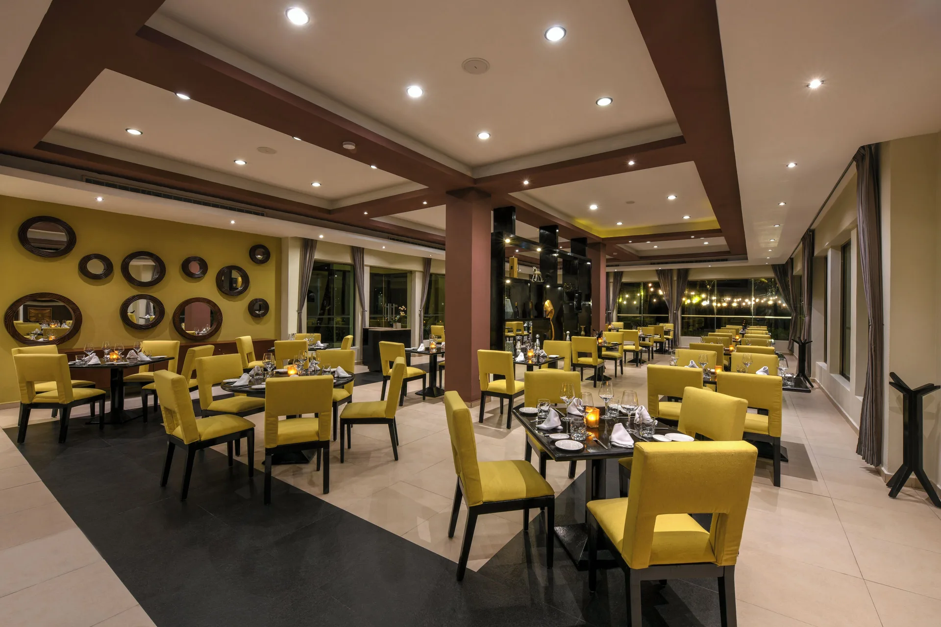 A modern restaurant dining room with yellow chairs at El Dorado Casitas Royale.