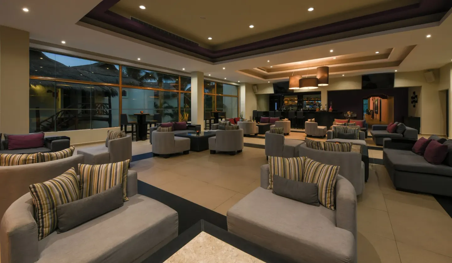 Spacious indoor lounge with armchairs, sofas, and a bar in the back at El Dorado Casitas Royale.