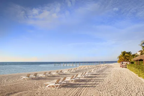 Rows of beach loungers line the shore at El Dorado Maroma Cenote, Underground Expedition.