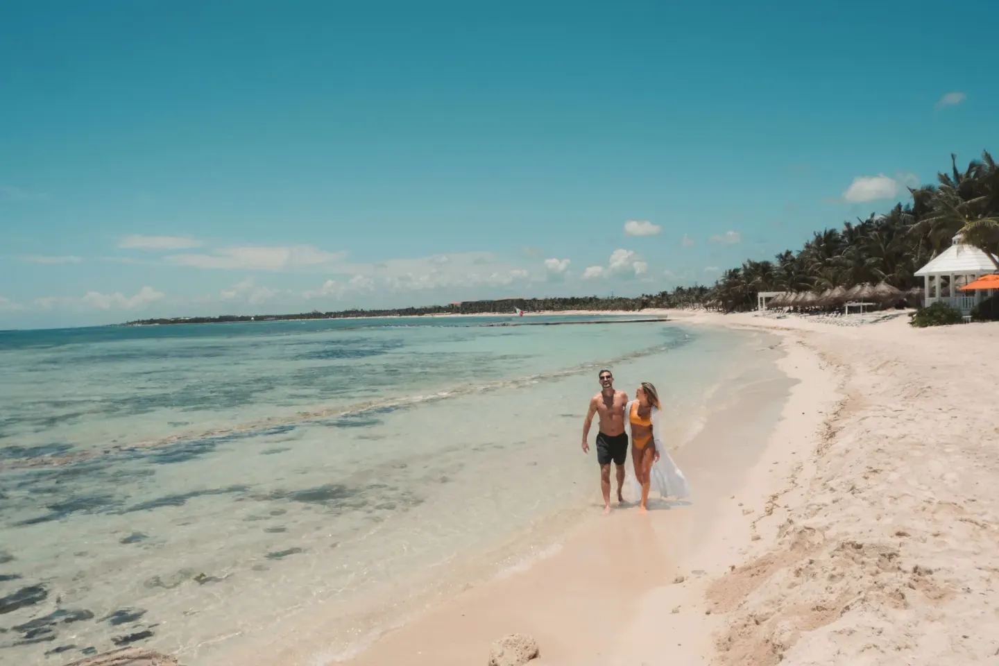 A couple walks along the beach at El Dorado Maroma Cenote, Underground Expedition.