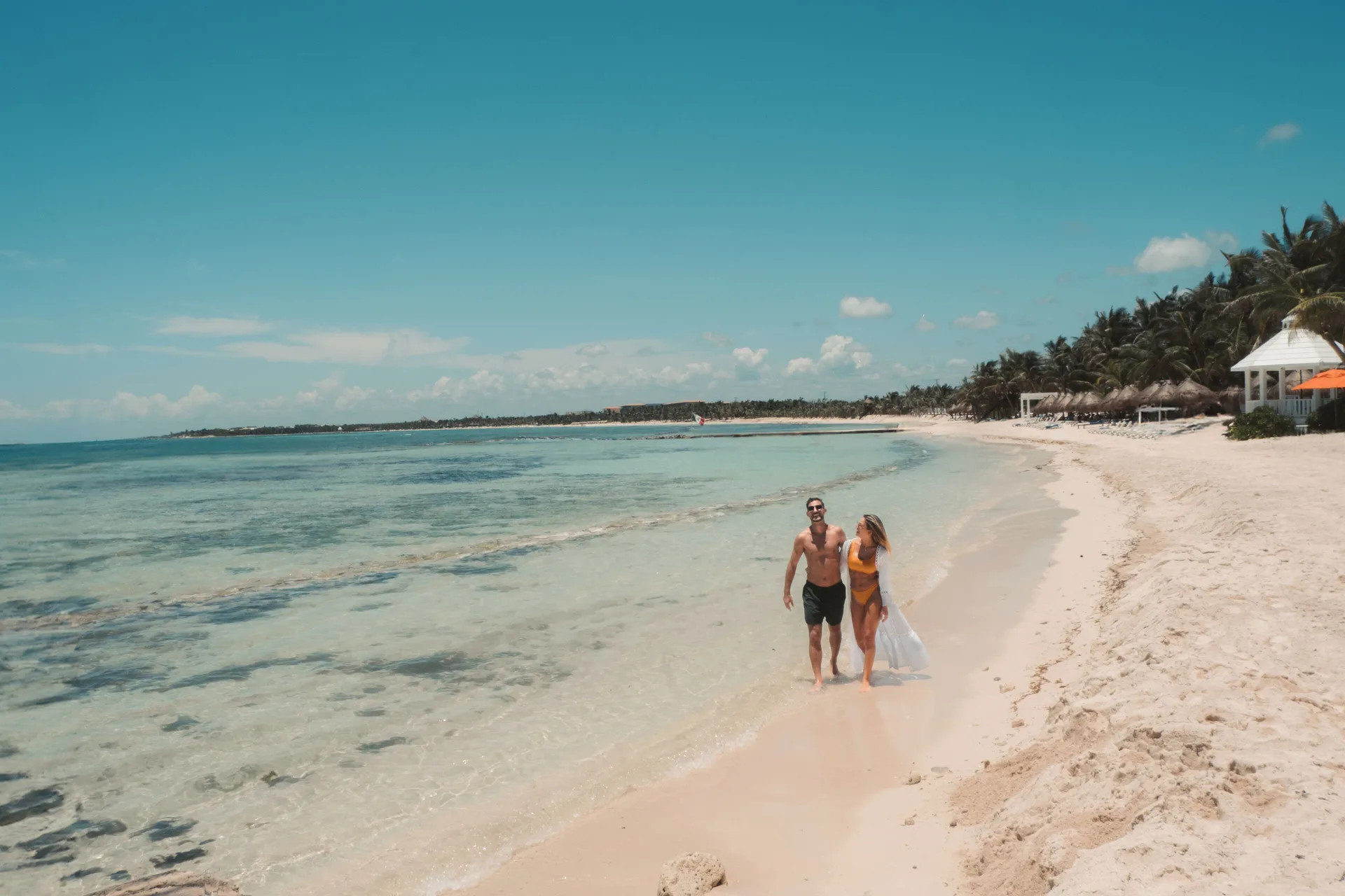 A couple walks along the beach at El Dorado Maroma Cenote, Underground Expedition.